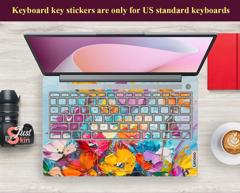 Puede incluir: Un teclado de port&aacute;til con pegatinas de teclas abstractas florales de colores. El teclado es gris y tiene el logotipo de Lenovo. El port&aacute;til est&aacute; abierto y la pantalla muestra un fondo rosa y blanco.