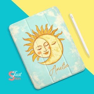 May include: A light blue iPad case featuring a watercolour design of a sun and moon with a smiling face. The case has the name "Amelia" written in cursive on the bottom right corner.