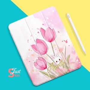 May include: A pink and white iPad case with a watercolor design of pink tulips and a white bunny. The case has the name "Amelia" written in gold lettering.