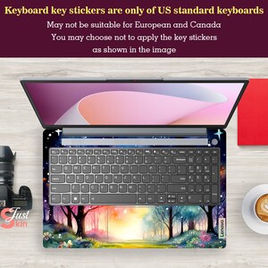 May include: A laptop computer with a keyboard featuring a colorful forest scene with trees, flowers, and a sunset. The keyboard is labeled "Lenovo". The text "Keyboard key stickers are only of US standard keyboards" is displayed above the laptop.
