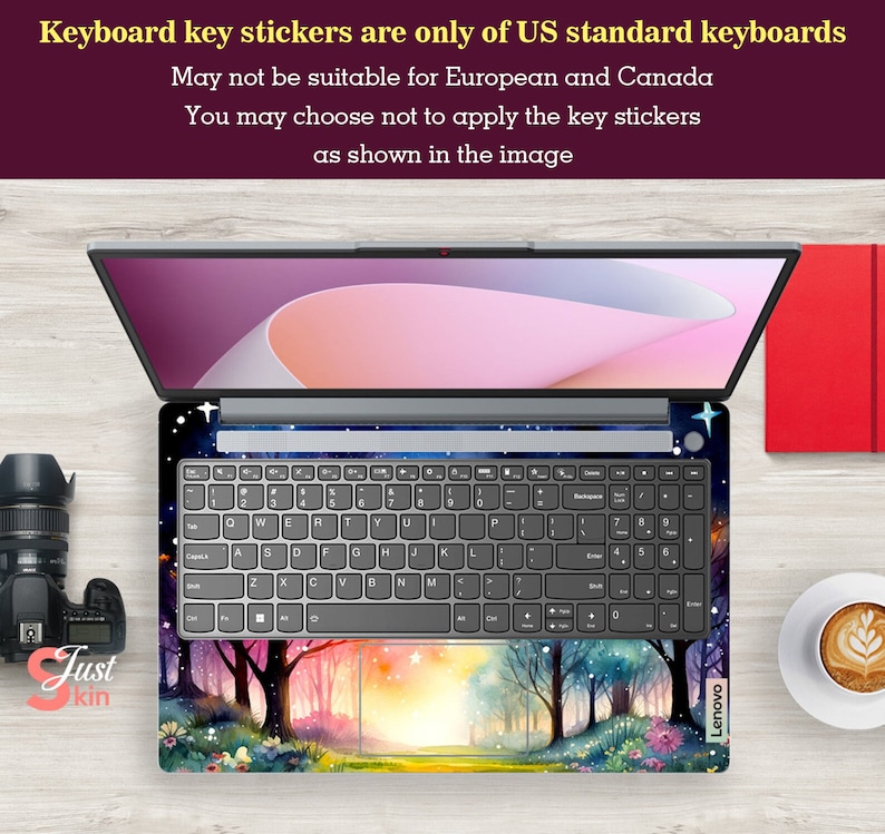 May include: A laptop computer with a keyboard featuring a colorful forest scene with trees, flowers, and a sunset. The keyboard is labeled "Lenovo". The text "Keyboard key stickers are only of US standard keyboards" is displayed above the laptop.