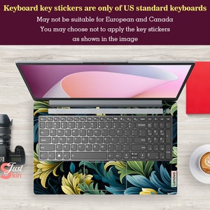 May include: A laptop keyboard with a floral design key sticker set. The keyboard is grey with black keys and the sticker set features a dark background with green, blue, and yellow floral patterns. The laptop is a Lenovo.