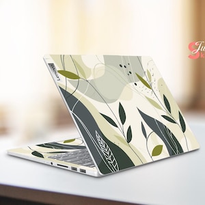 May include: A white laptop with a green and gray abstract floral design on the lid. The design features leaves and swirls. The laptop has the word "Lenovo" printed on the lid.