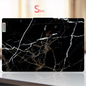 Puede incluir: Piel negra para port&aacute;til con un patr&oacute;n de m&aacute;rmol blanco. La piel tiene la palabra "Lenovo" impresa en el lado izquierdo.