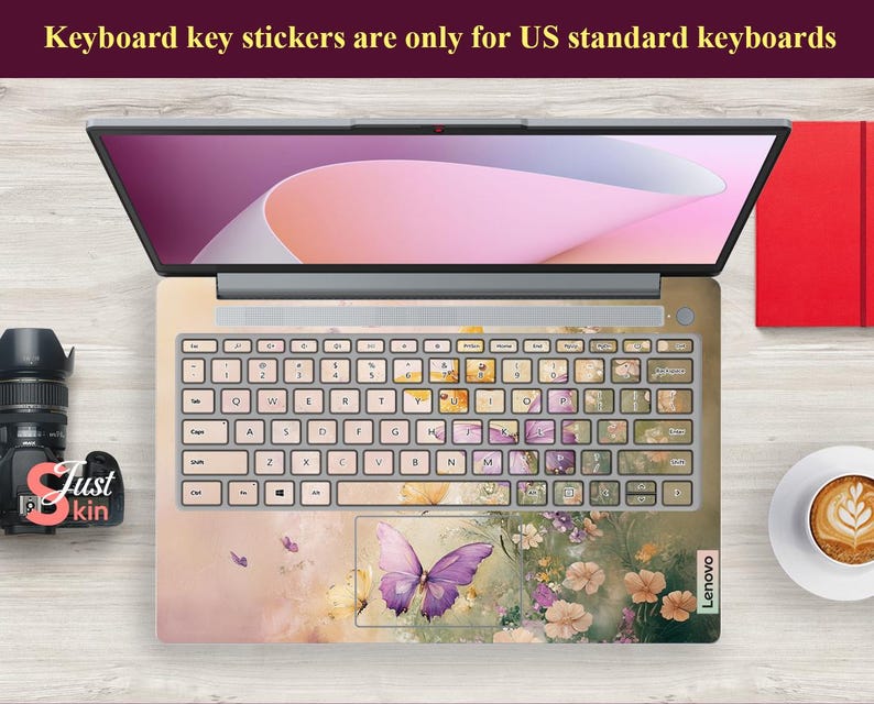 Puede incluir: Un teclado de port&aacute;til con una pegatina de teclado con dise&ntilde;o floral y de mariposa. La pegatina es rosa, amarilla y verde con una mariposa morada en el centro. El texto "Lenovo" es visible en el port&aacute;til.
