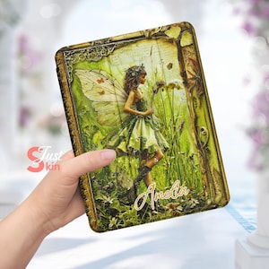 May include: A green and gold patterned book cover with a fairy illustration. The fairy is wearing a green dress and has wings. The cover has the name "Amelia" written on it.