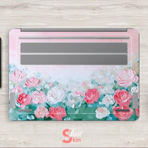 Peut inclure: Peau de protection pour ordinateur portable avec un motif floral compos&eacute; de fleurs roses, blanches et vertes sur un fond rose clair. Le motif est une peinture de style aquarelle.