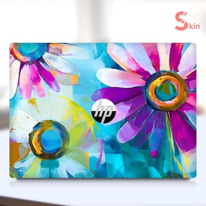 May include: A laptop skin with a colorful abstract floral design featuring pink, purple, blue, and yellow flowers. The HP logo is visible on the skin.