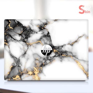May include: White laptop skin with a black and gold marble pattern. The HP logo is visible in the center of the skin.