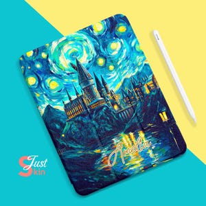 Puede incluir: Una funda para iPad azul y amarilla con una pintura del castillo de Hogwarts frente a un cielo estrellado. La funda tiene el nombre "Amelia" escrito en letras doradas.