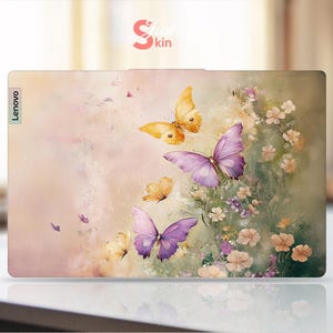 Puede incluir: Una piel para port&aacute;til rosa y blanca con un dise&ntilde;o floral con mariposas en tonos morados y amarillos. La piel tiene la palabra "Lenovo" impresa en el lado izquierdo.