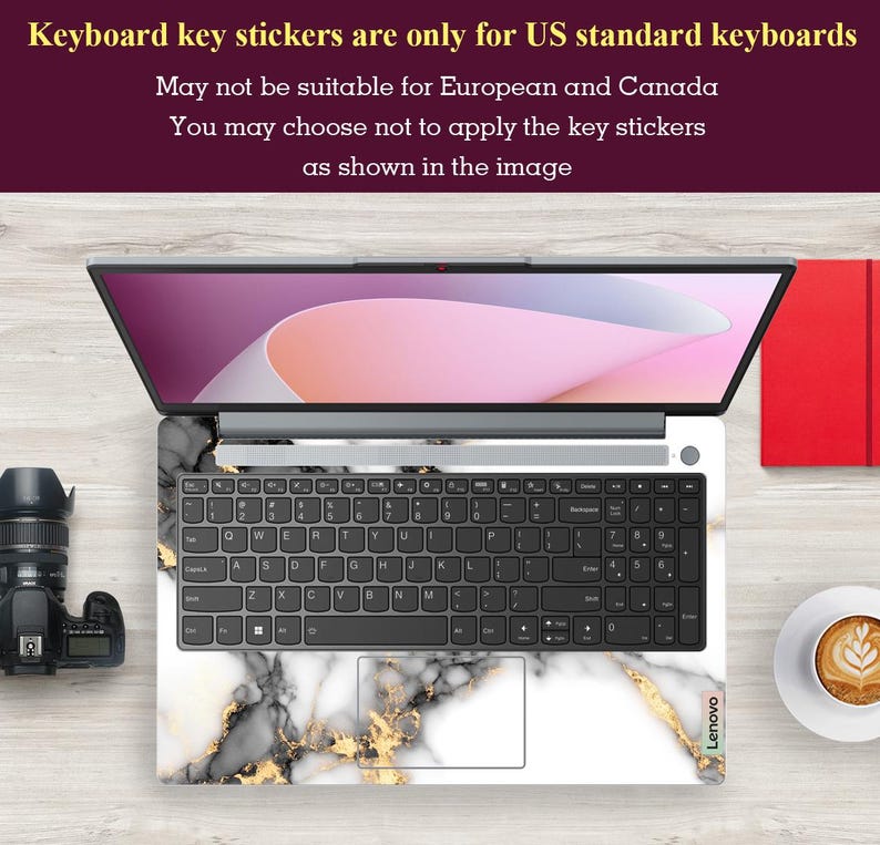 May include: A laptop computer with a white marble and gold keyboard sticker. The sticker has a black and white marble pattern with gold accents. The laptop is on a wooden surface. The text "Keyboard key stickers are only for US standard keyboards" is displayed at the top of the image. The text "May not be suitable for European and Canada" is displayed below the first line of text. The text "You may choose not to apply the key stickers as shown in the image" is displayed below the second line of text. The text "Lenovo" is displayed on the bottom right corner of the laptop.