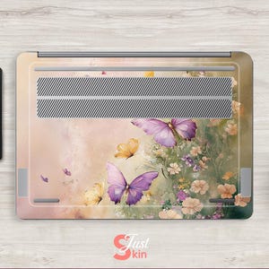 Puede incluir: Una piel para port&aacute;til con un dise&ntilde;o floral con mariposas en tonos morados y amarillos. El fondo es de un rosa suave con un sutil efecto acuarela.