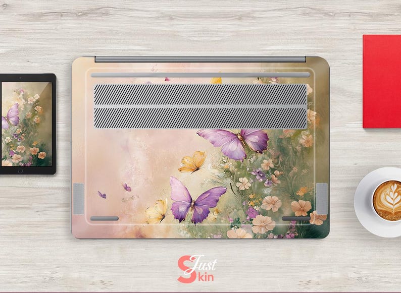 Puede incluir: Una piel para port&aacute;til con un dise&ntilde;o floral con mariposas en tonos morados y amarillos. El fondo es de un rosa suave con un sutil efecto acuarela.