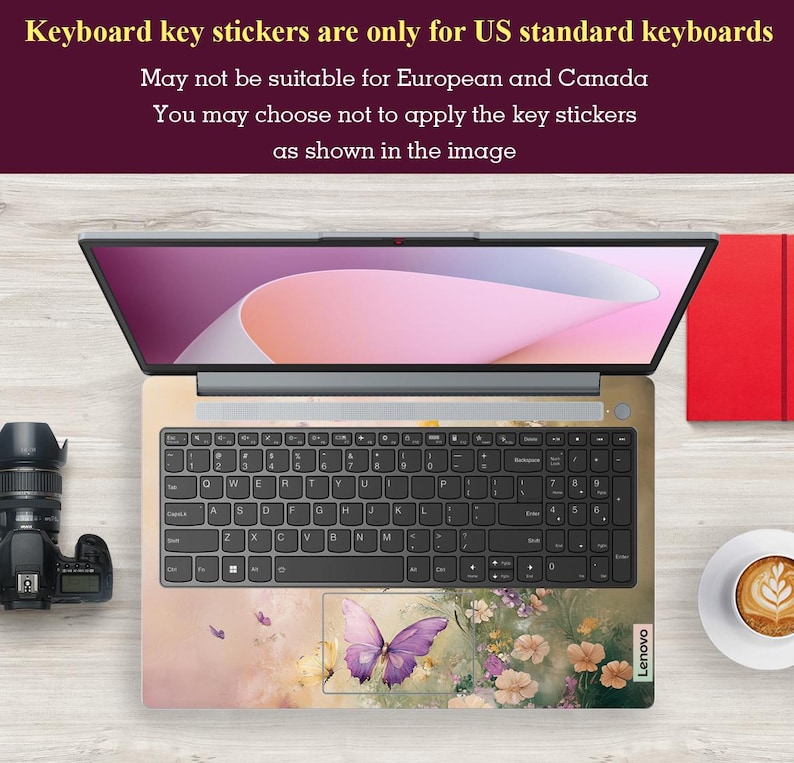 Puede incluir: Un teclado de port&aacute;til con una pegatina con dise&ntilde;o de mariposa. La pegatina es de color rosa claro y morado con una mariposa en el centro. El teclado es negro con letras blancas. El port&aacute;til es un Lenovo.