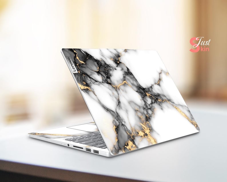 May include: A white laptop with a marble design and gold accents. The laptop is open and the screen is facing away from the viewer. The laptop has the word "Lenovo" printed on the side.