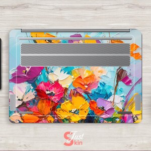 Puede incluir: Piel para port&aacute;til con un dise&ntilde;o floral abstracto colorido con flores de color rosa, amarillo, azul y morado brillantes sobre un fondo azul claro.