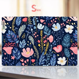 Op de afbeelding: Een Lenovo laptop skin met een bloemenpatroon. Het ontwerp bevat roze, witte en blauwe bloemen, samen met groene en gele bladeren, tegen een donkerblauwe achtergrond. Het woord "Skin" is zichtbaar in de rechterbovenhoek.