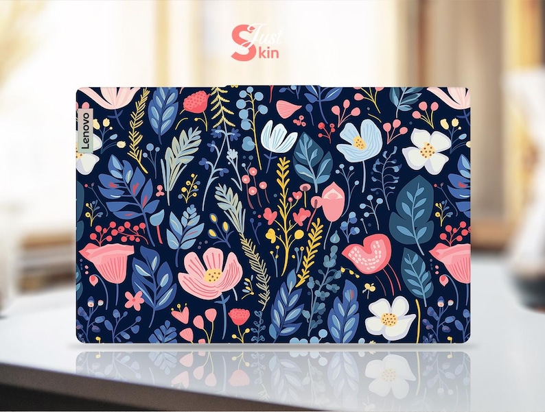 Op de afbeelding: Een Lenovo laptop skin met een bloemenpatroon. Het ontwerp bevat roze, witte en blauwe bloemen, samen met groene en gele bladeren, tegen een donkerblauwe achtergrond. Het woord "Skin" is zichtbaar in de rechterbovenhoek.