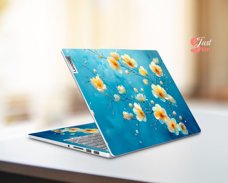 May include: A blue laptop with a floral design on the lid. The design features white flowers with yellow centers on a blue background. The laptop has the Lenovo logo on the lid.