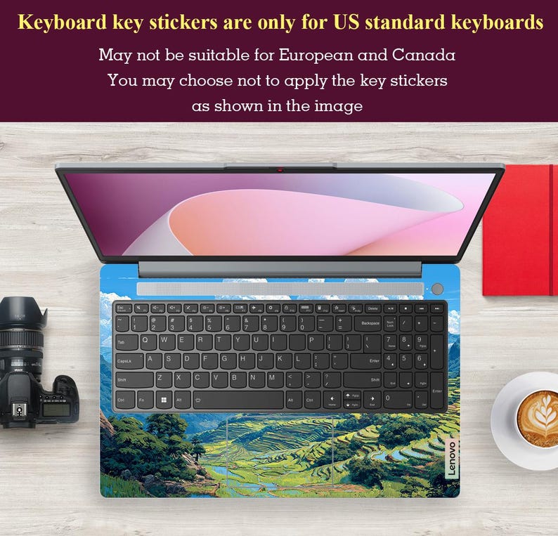 May include: Laptop with a keyboard skin featuring a landscape design of green terraced fields under a blue sky. The keyboard has black keys and the text "Lenovo" is visible. The screen displays a pink and white gradient. Text at the top states the keyboard stickers are for US keyboards.