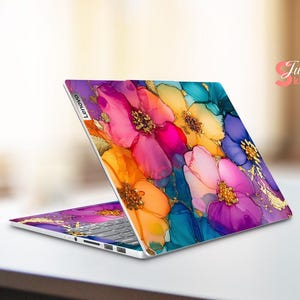May include: A Lenovo laptop with a vibrant floral design. The laptop's cover features a colorful pattern of pink, orange, yellow, blue, and purple flowers with gold accents. The keyboard is visible.