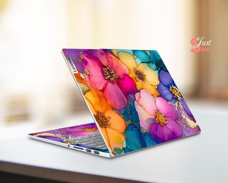 May include: A Lenovo laptop with a vibrant floral design. The laptop's cover features a colorful pattern of pink, orange, yellow, blue, and purple flowers with gold accents. The keyboard is visible.
