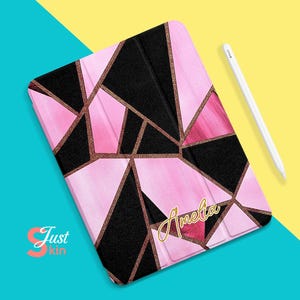 May include: A pink and black geometric iPad case with gold glitter accents. The case has the name "Amelia" written in gold glitter on the front.