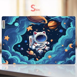 May include: A blue and white laptop skin featuring a cartoon astronaut cat floating in space. The skin has a galaxy design with stars, planets, and clouds. The text "Lenovo" is printed on the left side of the skin.
