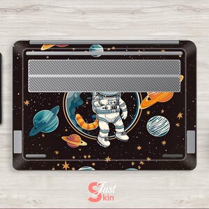 May include: A black laptop skin with a cartoon astronaut design, set against a backdrop of planets and stars. The image includes Saturn and Jupiter. A tablet with a similar space theme is also visible.
