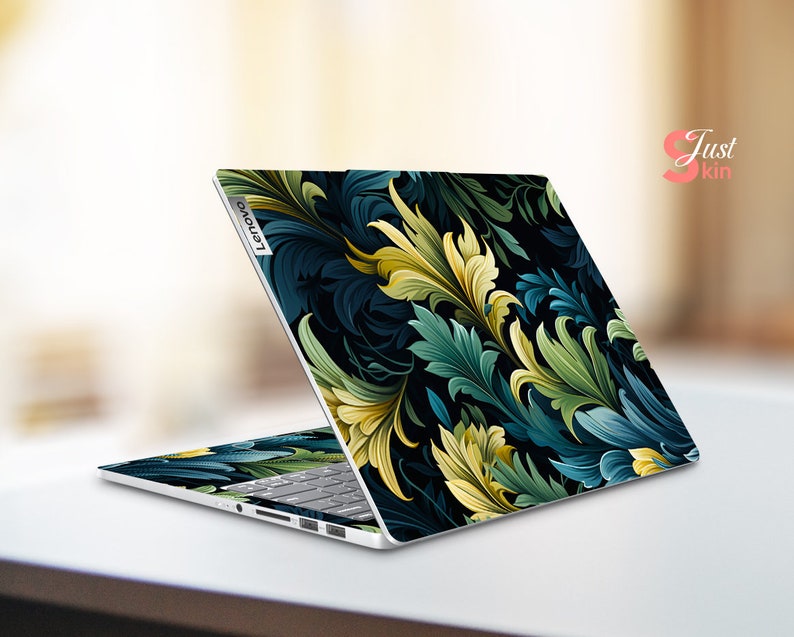May include: A laptop computer with a dark blue and green floral design on the lid. The design features intricate leaves and swirls. The laptop is closed and the Lenovo logo is visible on the lid.