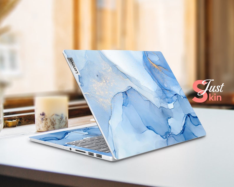 May include: A blue and gold laptop skin with a marble-like design. The skin is applied to a silver Lenovo laptop.
