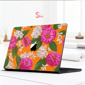 May include: Laptop skin featuring a vibrant floral pattern. The design showcases large pink and white flowers with green leaves against a bright orange background. The Apple logo is visible. The brand name "Just Skin" is in the top right corner.