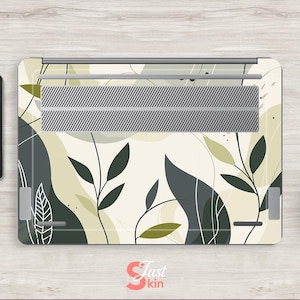 May include: Laptop skin with a white background and a pattern of green and gray leaves. The skin has a silver metal vent in the center.