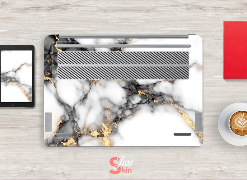 May include: White laptop skin with a marble pattern featuring black and gold veins. The skin has a silver vent cover.