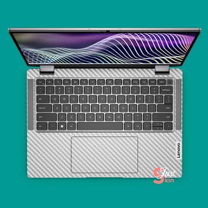 May include: A silver laptop computer with a white carbon fiber skin. The laptop is open and the screen is displaying a purple and white abstract design. The keyboard is visible and the laptop has the Lenovo logo on the bottom right corner.