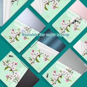 May include: Laptop skins with a floral design. The skins feature a light green background with a watercolor-style branch of white and pink flowers. The text "Suitable for most laptop" is visible.