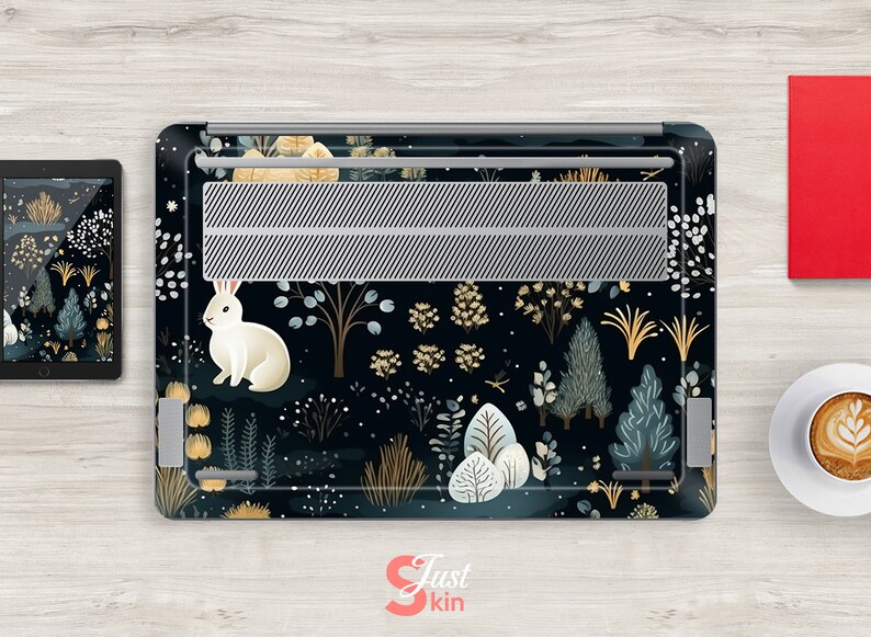 May include: Laptop skin with a whimsical forest design featuring a white rabbit, trees, and foliage in shades of blue, gold, and white against a dark background. A tablet with a matching design is also visible.