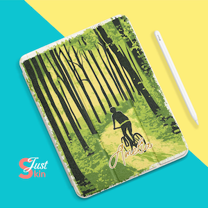 Peut inclure: Une coque d'iPad verte et jaune avec une silhouette d'une personne à vélo dans une forêt. La coque est personnalisée avec le nom "Amelia" en lettres dorées.