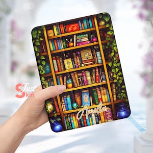 Puede incluir: Una funda para tablet colorida con un diseño de estantería que presenta una variedad de libros, plantas y el nombre "Amelia" escrito en letras doradas.