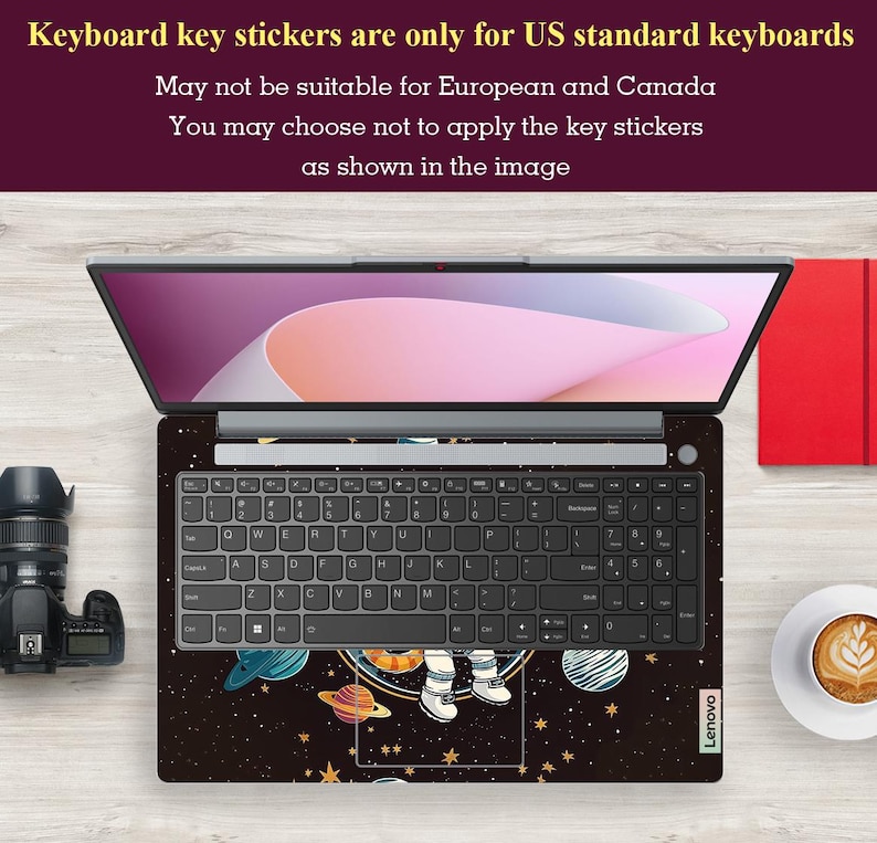 May include: Laptop with a space-themed keyboard skin showing planets, stars, and an astronaut. The keyboard has black keys and the screen displays a pink and white gradient. Text at the top indicates the stickers are for US keyboards.