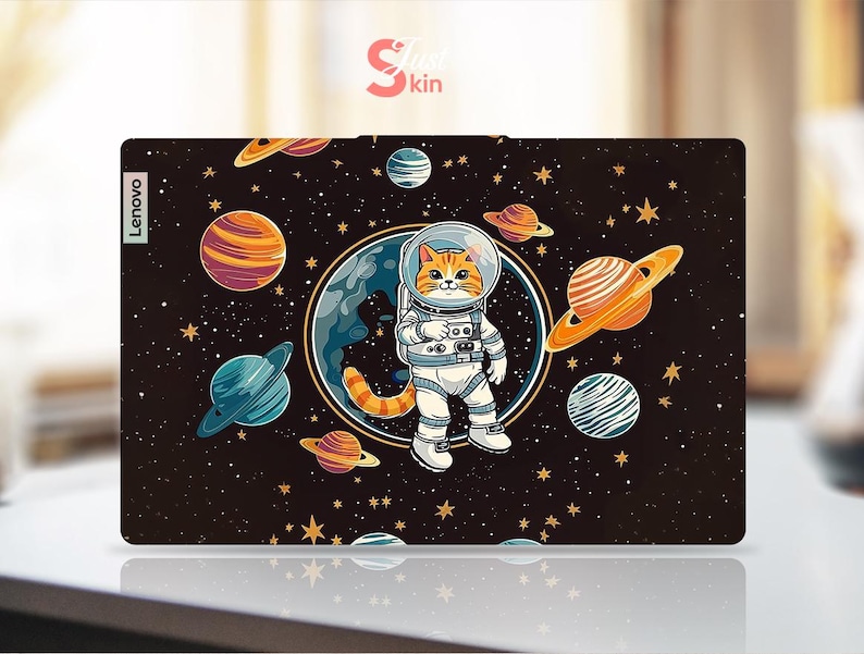 May include: A Lenovo laptop skin with a cartoon cat astronaut in a spacesuit, set against a backdrop of planets and stars on a dark background. The skin has the text "Skin Kin" and the Lenovo logo.