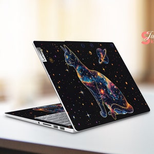 May include: A black laptop with a galaxy-themed design featuring a cat with a colorful nebula pattern. The laptop has a silver Lenovo logo on the back.