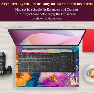 May include: Laptop with a floral design keyboard skin. The skin features a colorful abstract floral pattern with shades of purple, orange, blue, and gold. The laptop is open, displaying the screen and keyboard. Text at the top states: "Keyboard key stickers are only for US standard keyboards."