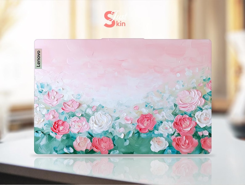 Peut inclure: Une peau d'ordinateur portable &agrave; fleurs roses et vertes avec le mot "Lenovo" en blanc sur le c&ocirc;t&eacute; gauche.