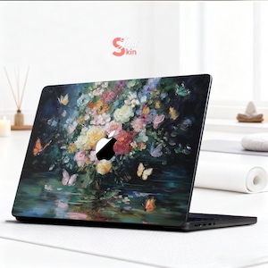 May include: A black laptop with a floral design featuring colorful flowers and butterflies. The design covers the lid of the laptop, with the Apple logo visible. The laptop is on a white surface.