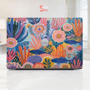 May include: A Dell laptop featuring a vibrant, colorful skin with an underwater coral reef pattern. The design includes various fish, sea plants, and coral in shades of blue, orange, pink, and yellow. The text Just Skin is visible at the top.