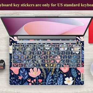 Op de afbeelding: Laptop toetsenbord skin met een bloemenpatroon in marineblauw, roze en wit. De toetsen van het toetsenbord zijn bedekt met stickers. De tekst bovenaan luidt: "Keyboard key stickers are only for US standard keyboards."