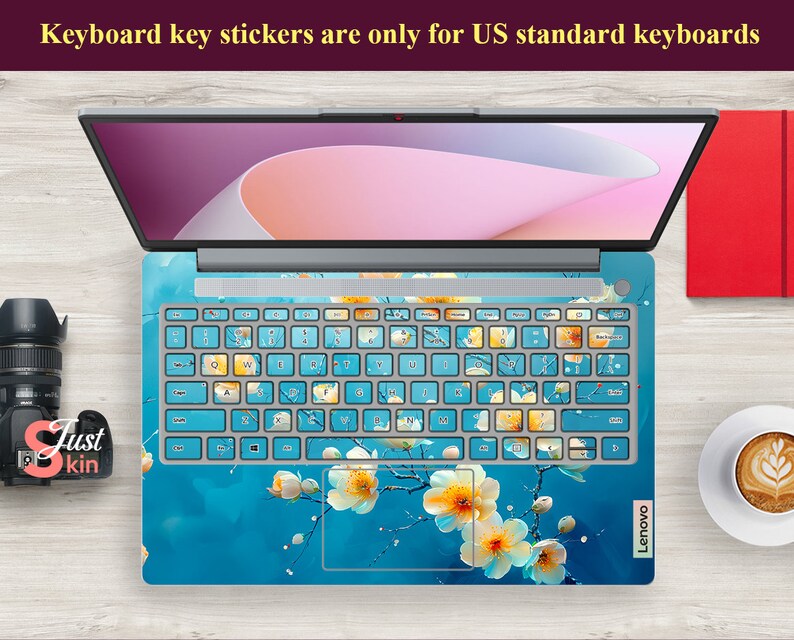 May include: A laptop computer with a blue and white floral keyboard sticker. The sticker features a design of white flowers with yellow centers on a blue background. The text "Keyboard key stickers are only for US standard keyboards" is displayed at the top of the image.