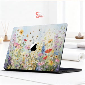 May include: Laptop skin featuring a vibrant floral design with pink, yellow, red, and blue flowers, and butterflies. The skin has the text "Just Skin" in the upper right corner. The Apple logo is visible.